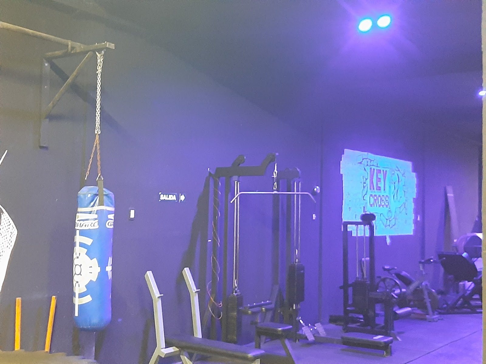Sala de Key Fit Gym con bolsa de boxeo, aparatos de musculacion y el mural KEY FIT CROSS